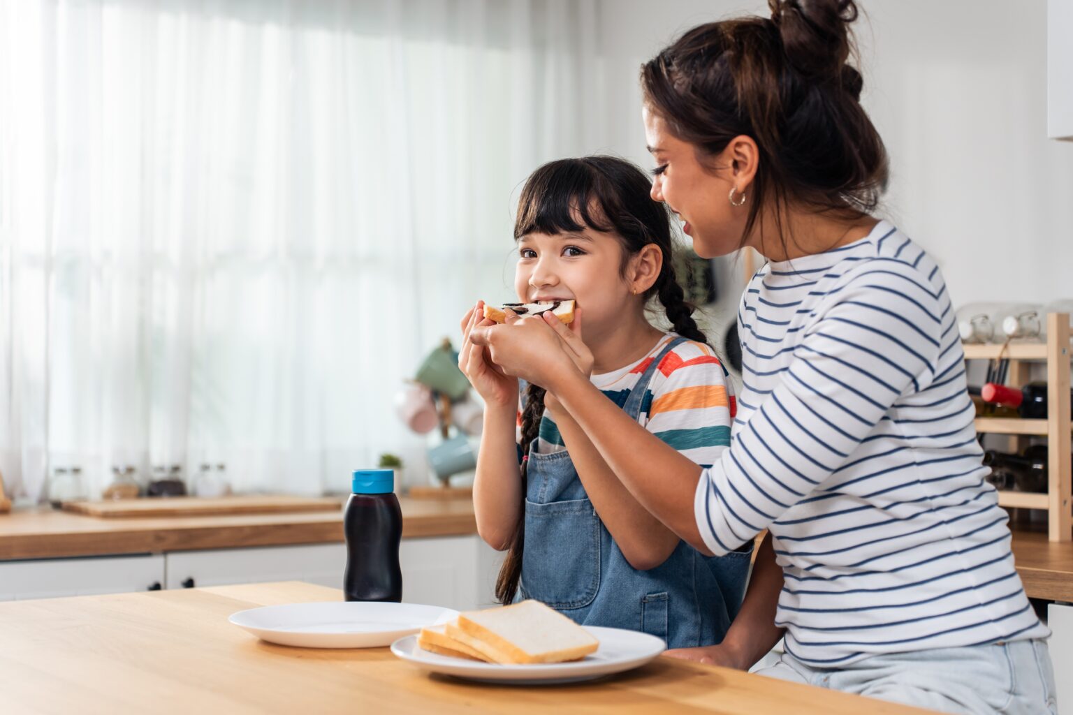 Mãe e filha comendo um pão saudável